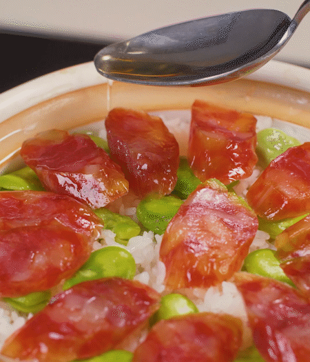 大米出現(xiàn)小孔時(shí)開(kāi)蓋放香腸，往鍋邊淋入少許油，再燜煮8~10分鐘左右。