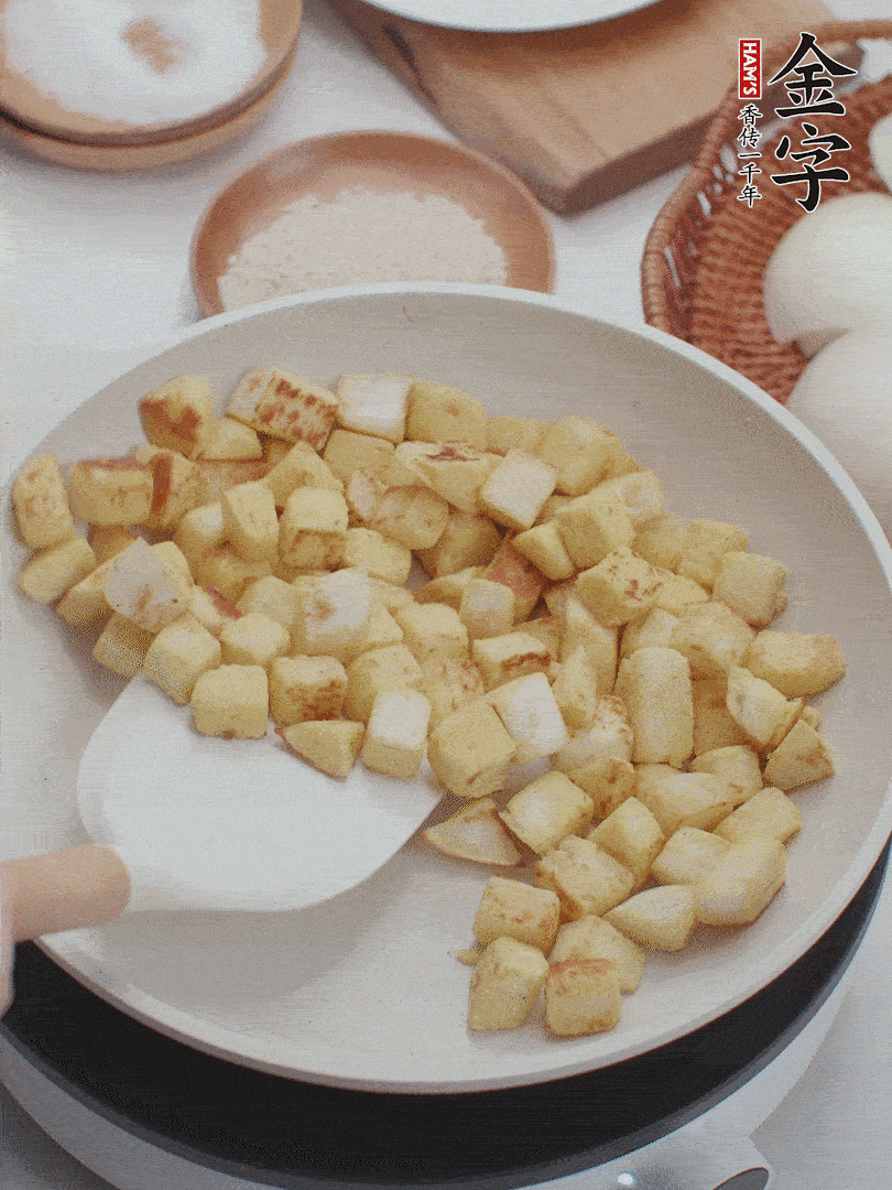 起鍋熱油，倒入饅頭丁，小火煎至蛋液凝固定型再翻面，饅頭丁部煎至金黃時(shí)盛起待用。