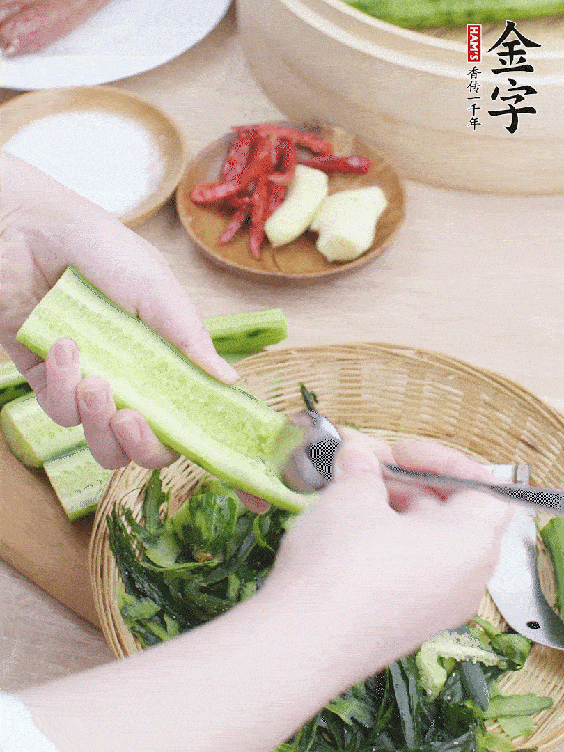 黃瓜削皮，對半切開，勺子挖去內(nèi)瓤，斜刀切片。青蒜斜刀切段。