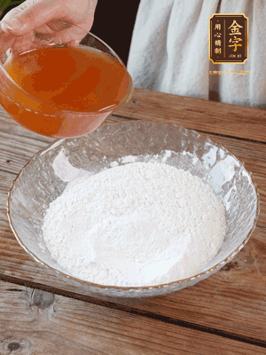 轉(zhuǎn)化糖漿、枧水、花生油攪拌均勻，加入面粉混合，醒發(fā)2小時(shí)。捏成23g一個(gè)的小球